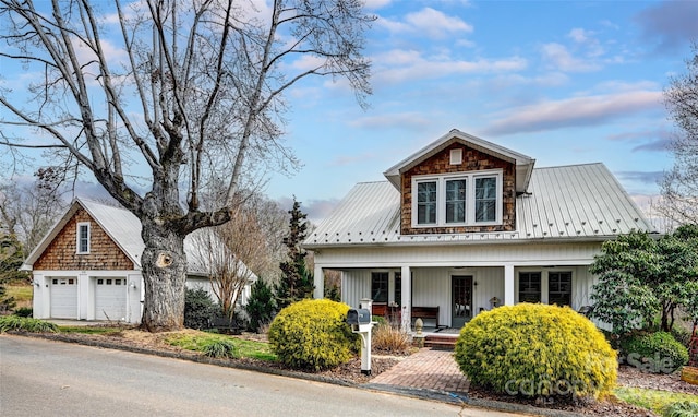 view of front facade featuring a garage, metal roof, and a porch