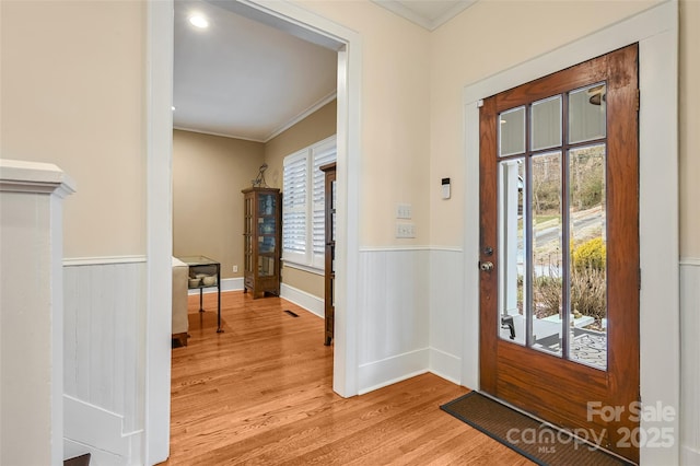 entryway featuring ornamental molding, wainscoting, and wood finished floors