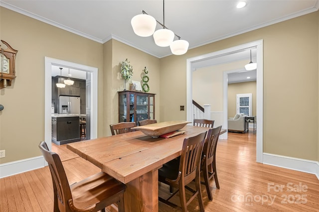 dining space with ornamental molding, light wood-style flooring, and baseboards