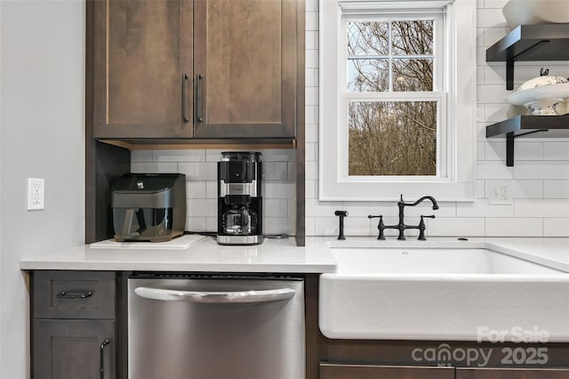 kitchen with light countertops, decorative backsplash, stainless steel dishwasher, a sink, and dark brown cabinets