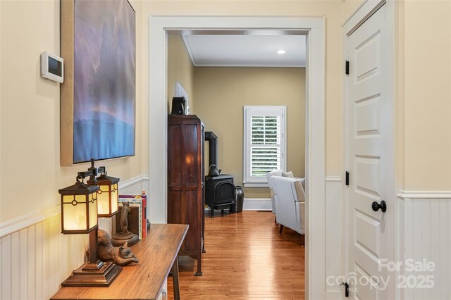 hall with ornamental molding, wainscoting, and wood finished floors