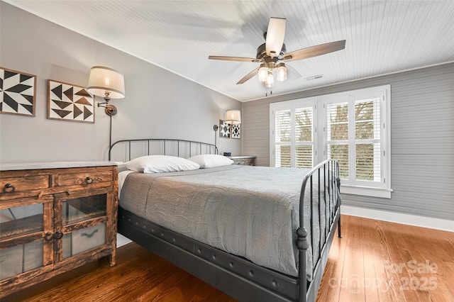 bedroom with ceiling fan, wood-type flooring, visible vents, and baseboards