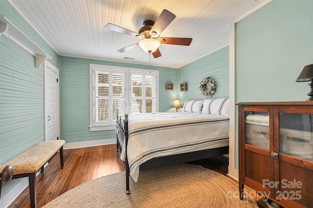 bedroom featuring baseboards, wood finished floors, visible vents, and a ceiling fan