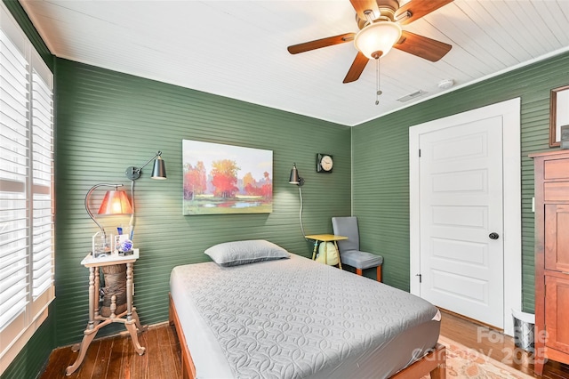 bedroom featuring a ceiling fan, visible vents, and wood finished floors