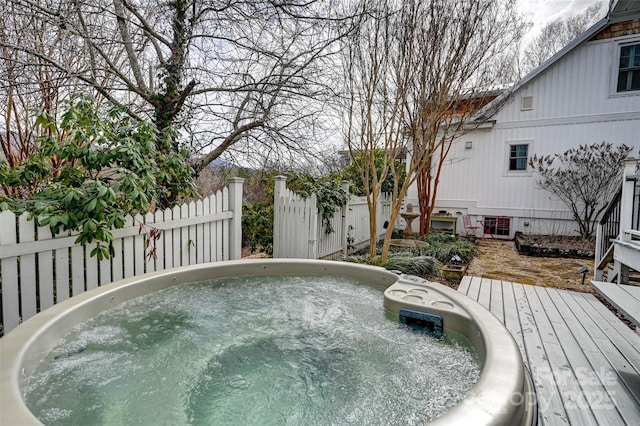 view of pool with hot tub deck surround, a wooden deck, and fence