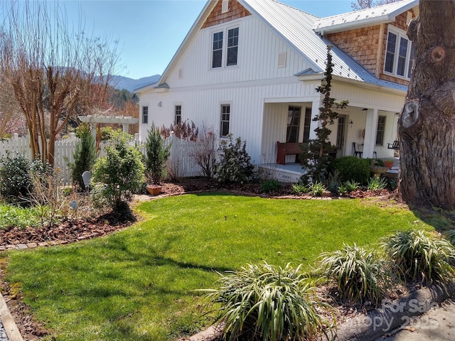 rear view of house featuring a porch, a lawn, fence, metal roof, and a pergola