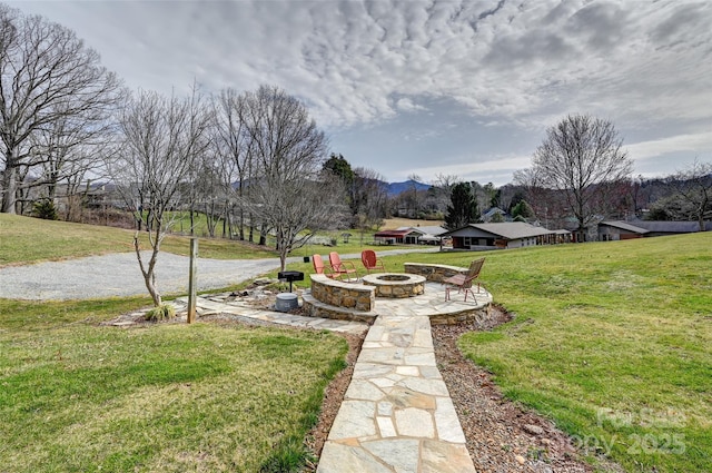 view of home's community featuring a lawn, a fire pit, and a mountain view