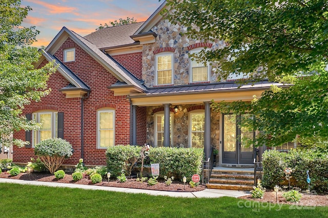 view of front of home featuring french doors, stone siding, brick siding, and a standing seam roof