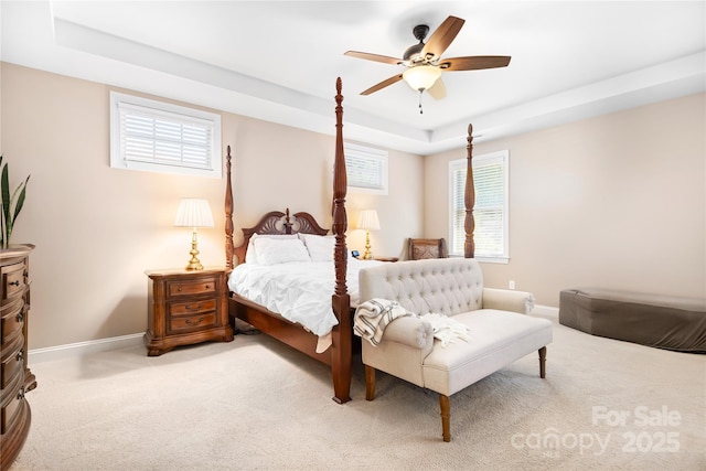 bedroom featuring baseboards, a raised ceiling, and light colored carpet