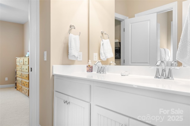 bathroom featuring double vanity, baseboards, and a sink