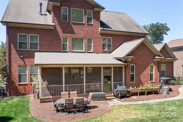 back of property featuring a patio area, a lawn, a shingled roof, and a sunroom