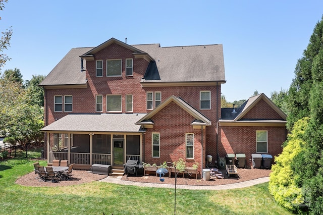 rear view of house featuring roof with shingles, a yard, and a sunroom