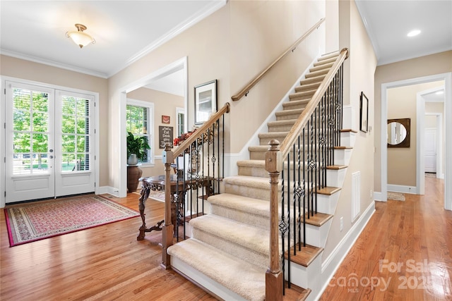 foyer featuring stairs, baseboards, crown molding, and light wood finished floors