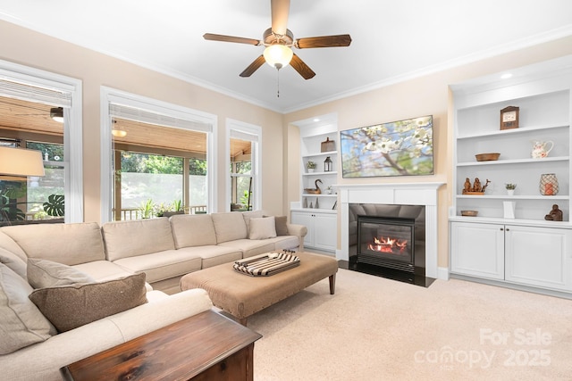 living area featuring a fireplace with flush hearth, built in shelves, carpet floors, and crown molding