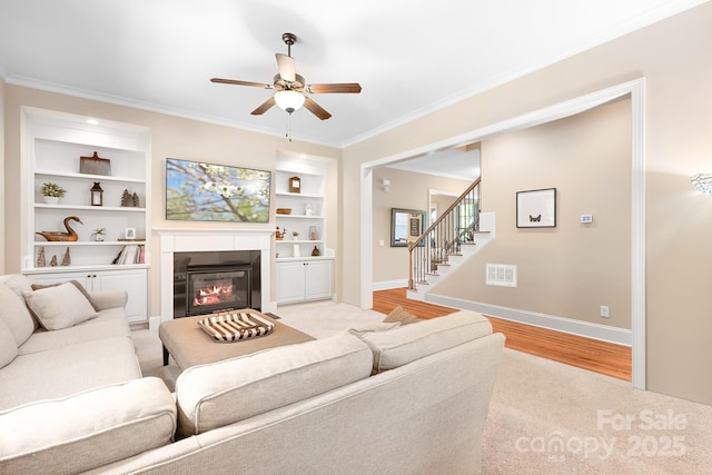 living room featuring stairway, built in features, baseboards, ornamental molding, and light wood-style floors