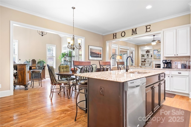 kitchen featuring stainless steel dishwasher, white cabinets, light wood-type flooring, and a sink