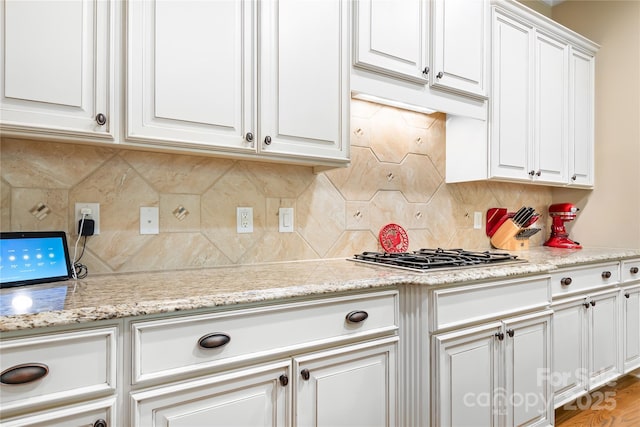 kitchen featuring light stone counters, decorative backsplash, and white cabinets