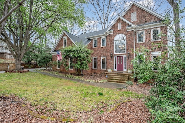 view of front facade with brick siding and a front lawn