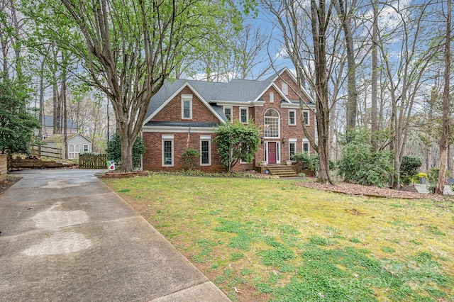 view of front of home featuring driveway, a front yard, and brick siding