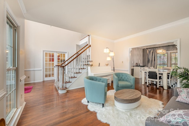 living room featuring stairs, crown molding, french doors, wood finished floors, and baseboards