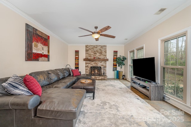 living room with visible vents, a fireplace, ornamental molding, and a ceiling fan