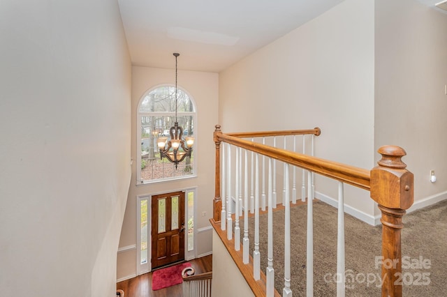 foyer with baseboards, a wealth of natural light, wood finished floors, and a chandelier