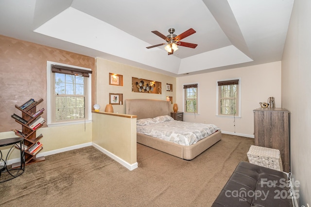 carpeted bedroom with a tray ceiling, baseboards, and ceiling fan