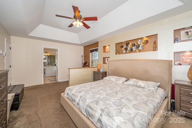 carpeted bedroom featuring a ceiling fan, a tray ceiling, baseboards, and connected bathroom