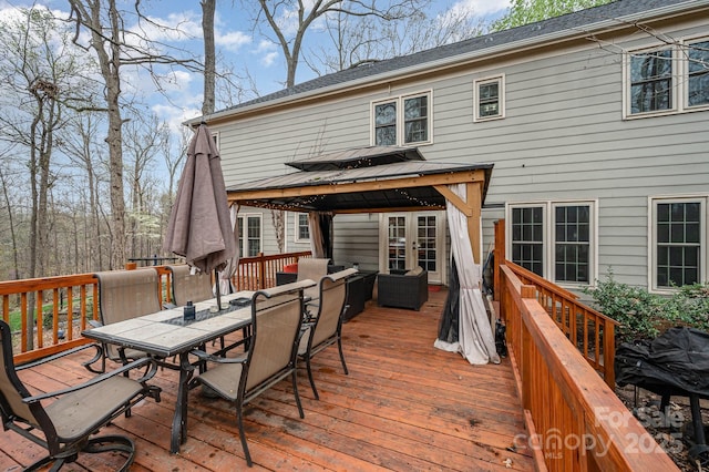wooden terrace featuring a gazebo, outdoor dining area, and french doors
