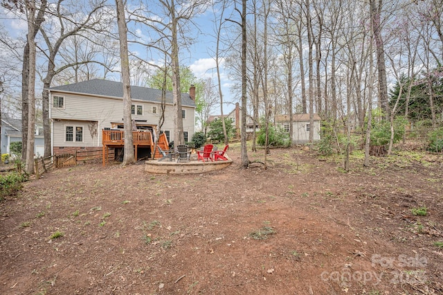 view of yard featuring an outdoor structure, a fire pit, fence, and a deck