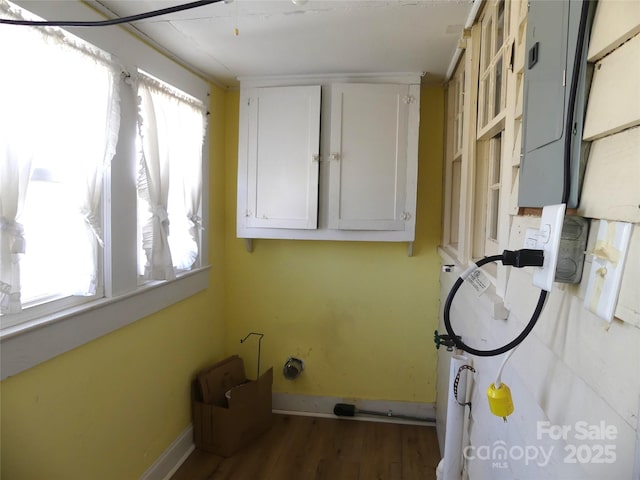 laundry area featuring a wealth of natural light, electric panel, baseboards, and wood finished floors