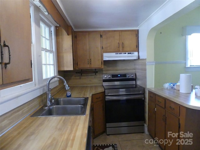 kitchen with under cabinet range hood, a sink, stainless steel range with electric cooktop, light countertops, and a wealth of natural light