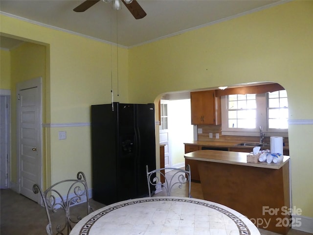 kitchen with crown molding, arched walkways, black refrigerator with ice dispenser, and a sink