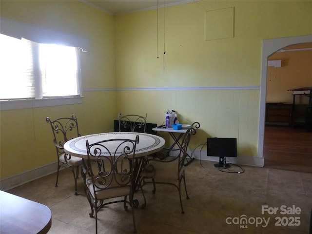 tiled dining room with a wainscoted wall and arched walkways