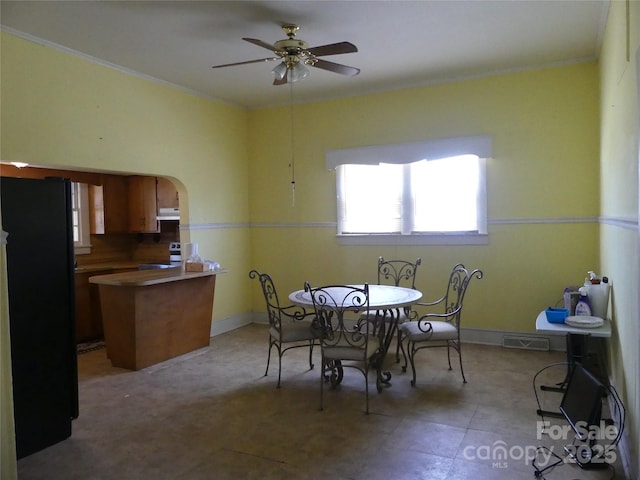 dining room featuring a ceiling fan, visible vents, arched walkways, and crown molding