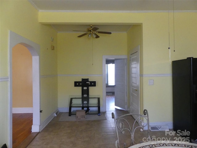 exercise area featuring baseboards, visible vents, arched walkways, ceiling fan, and ornamental molding