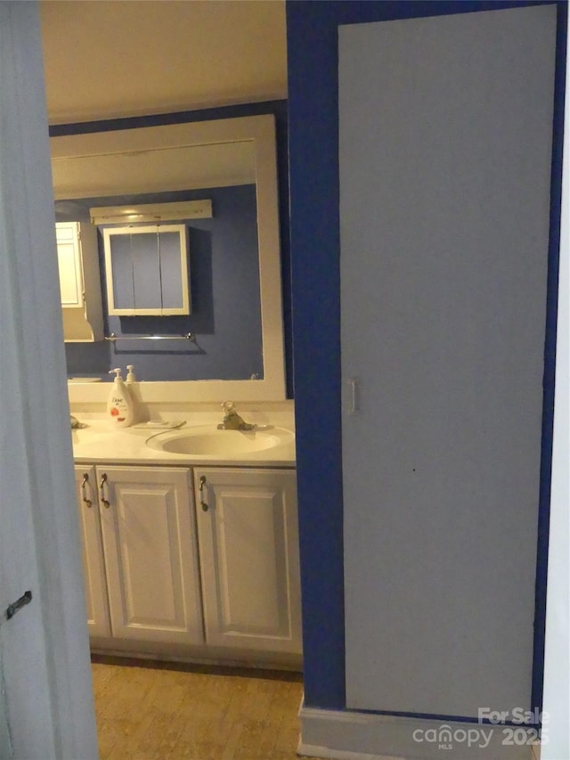 bathroom featuring double vanity, a sink, and wood finished floors