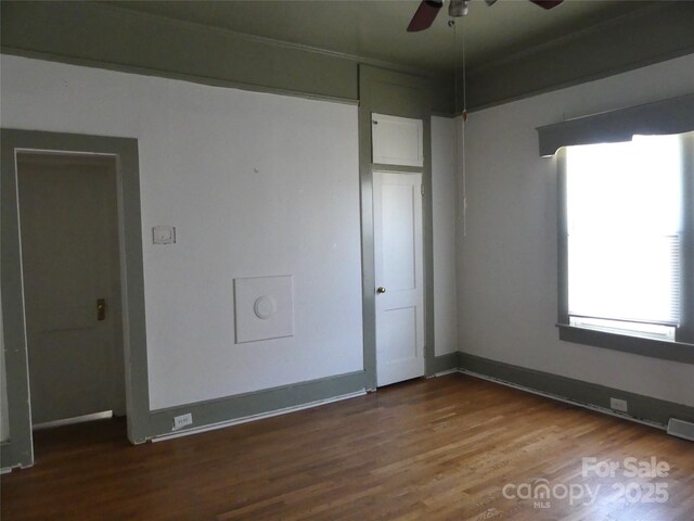 spare room featuring a ceiling fan, visible vents, baseboards, and wood finished floors