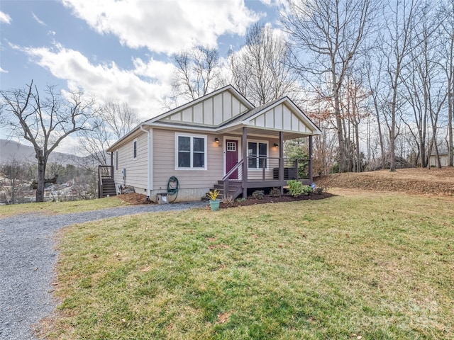 view of front of property with board and batten siding, covered porch, driveway, and a front lawn