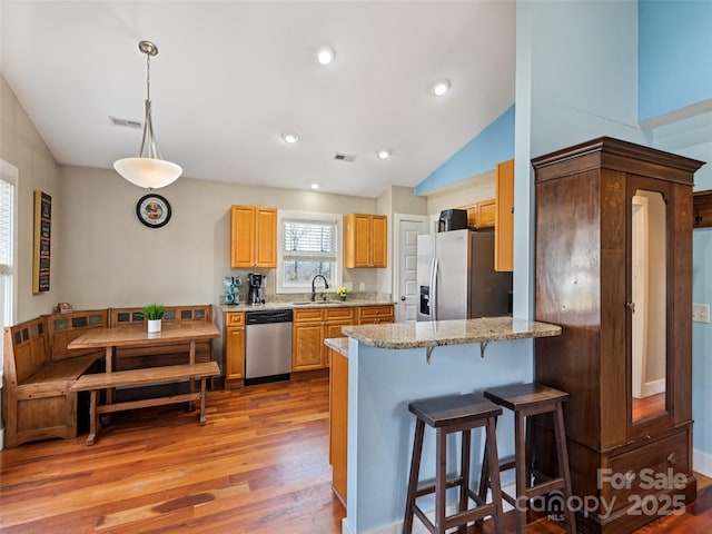 kitchen with light wood-type flooring, a kitchen bar, visible vents, and stainless steel appliances