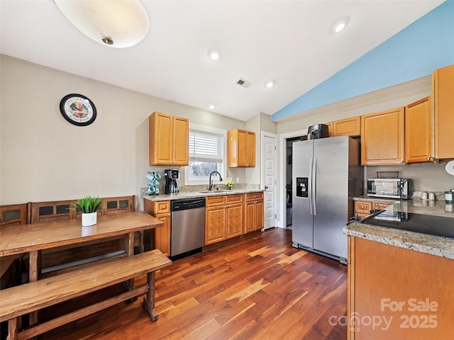 kitchen featuring dark wood-type flooring, a sink, visible vents, vaulted ceiling, and appliances with stainless steel finishes