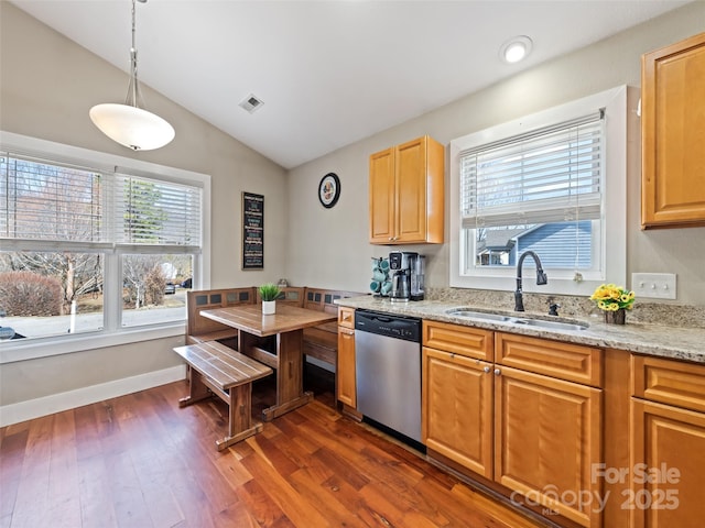 kitchen featuring visible vents, dishwasher, lofted ceiling, light stone counters, and a sink