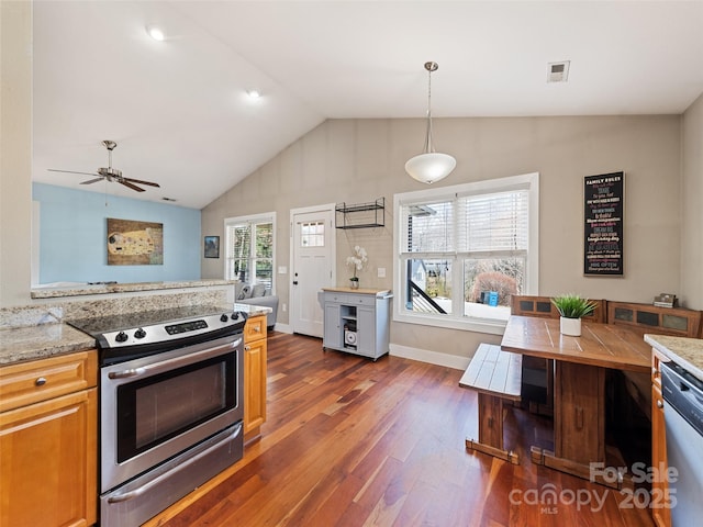 kitchen with light stone counters, dark wood-style floors, lofted ceiling, visible vents, and appliances with stainless steel finishes