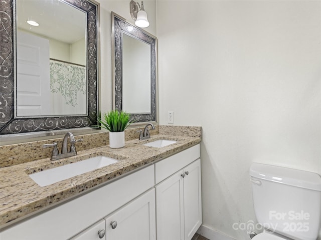 bathroom with double vanity, a sink, and toilet