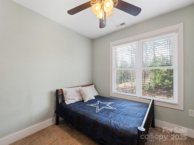 bedroom with a ceiling fan, wood finished floors, visible vents, and baseboards