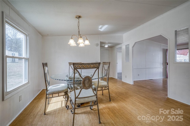 dining space featuring an inviting chandelier, ornamental molding, and wood finished floors