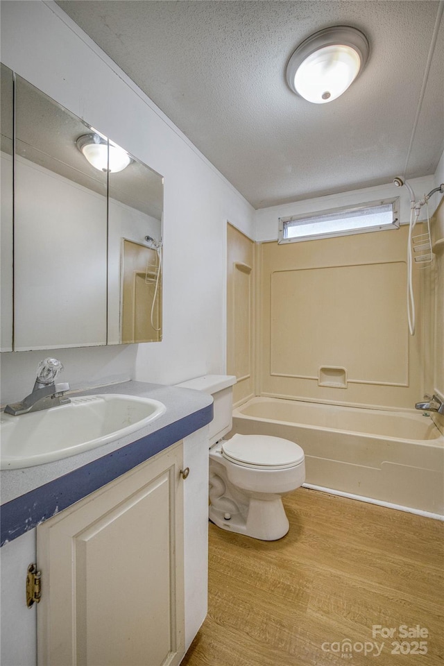 full bath with toilet, a textured ceiling, bathtub / shower combination, and wood finished floors