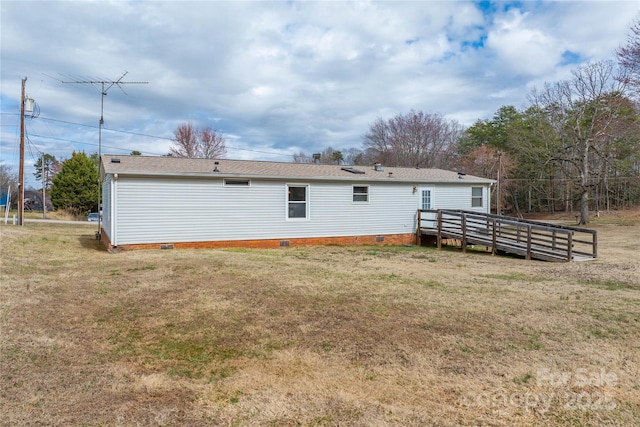 rear view of house featuring crawl space, a deck, and a lawn