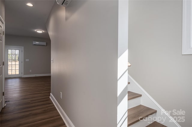 stairway featuring an AC wall unit, wood finished floors, and baseboards