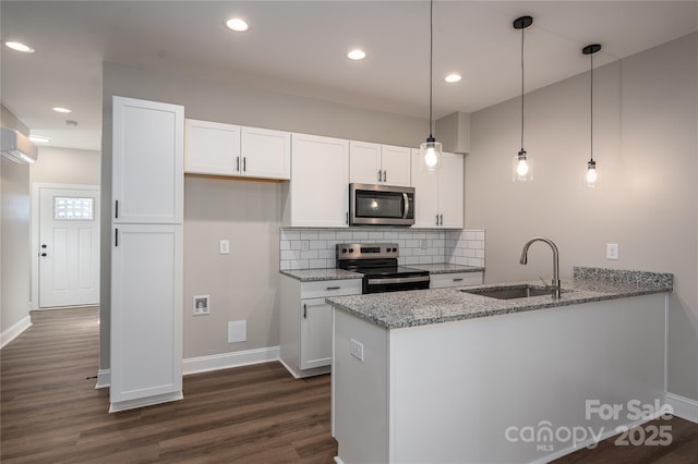 kitchen with a peninsula, a sink, white cabinetry, appliances with stainless steel finishes, and decorative backsplash